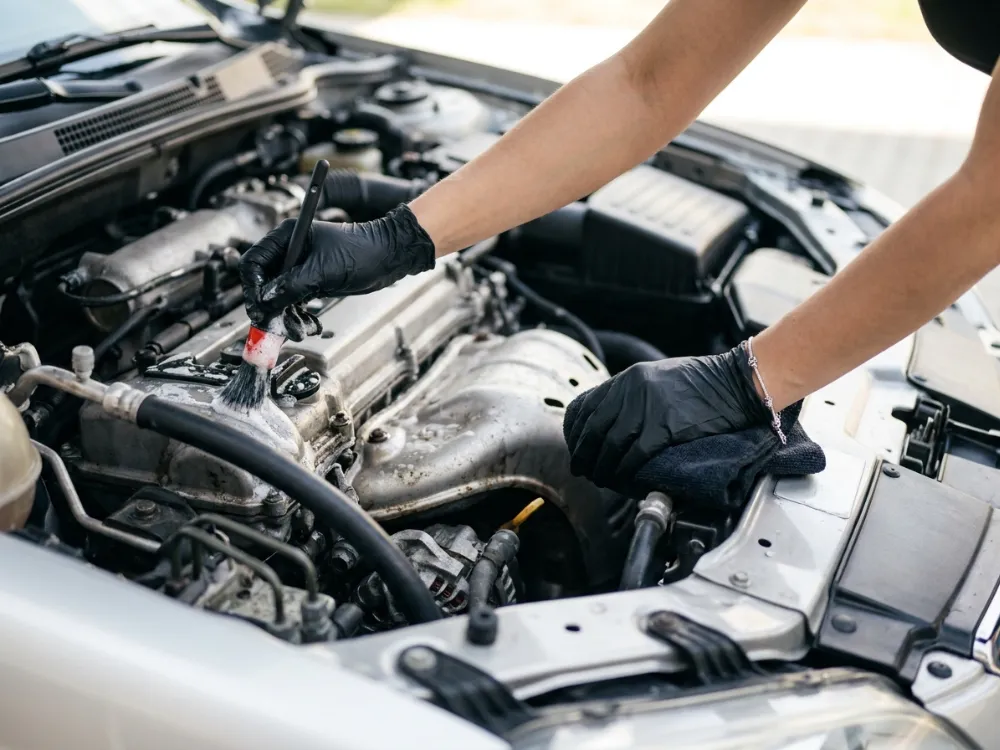 Detailer brushing an engine bay clean with a detailing brush