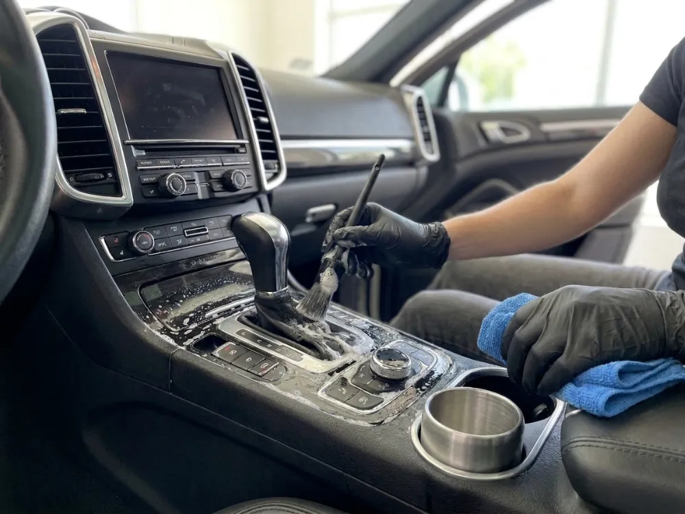 Detailer cleaning the centre console and gear shifter of a car interior